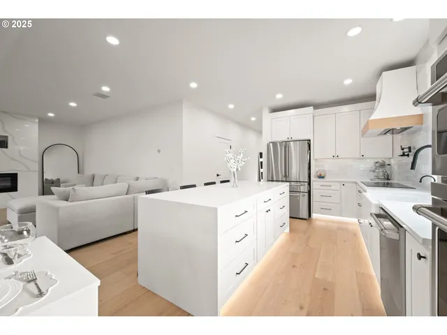 a large white kitchen with kitchen island a sink a stove a refrigerator cabinets and a dining table