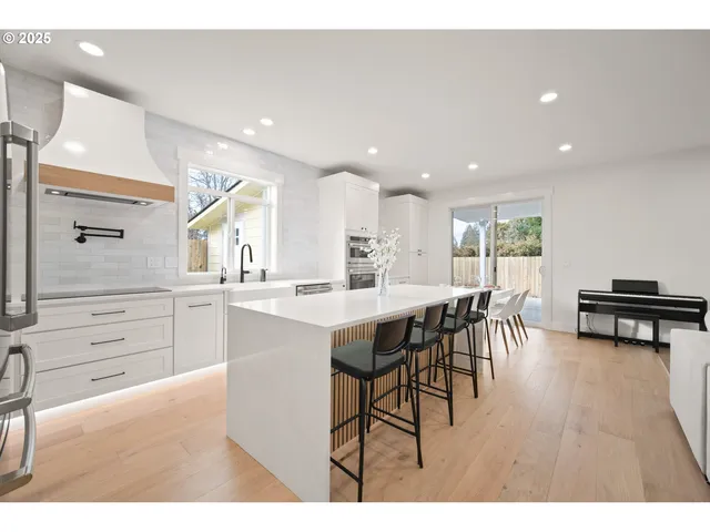 a kitchen with stainless steel appliances kitchen island granite countertop a table chairs sink and cabinets