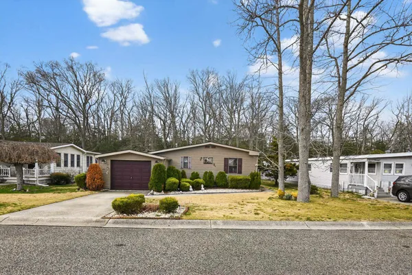 a front view of house with yard and trees in the background