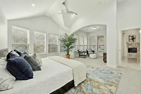 a bedroom with a bed a chandelier and large mirror with wooden floor