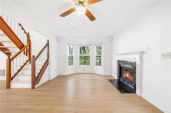 a view of an empty room with wooden floor fireplace and a window