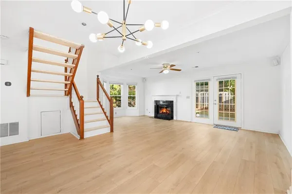 a view of an empty room with wooden floor fireplace and a window