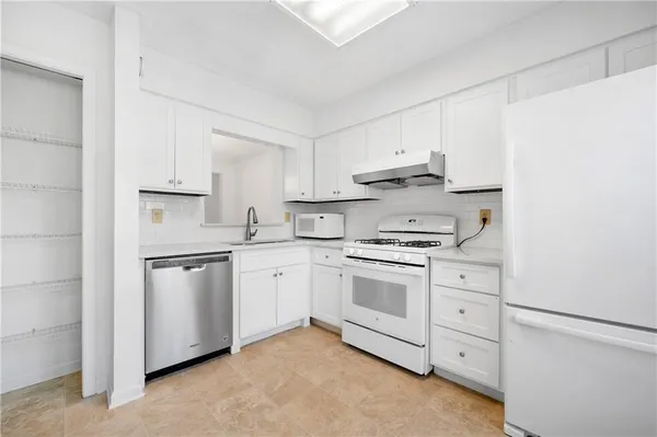a kitchen with granite countertop white cabinets and white appliances