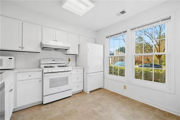 a kitchen with stainless steel appliances white cabinets and a window