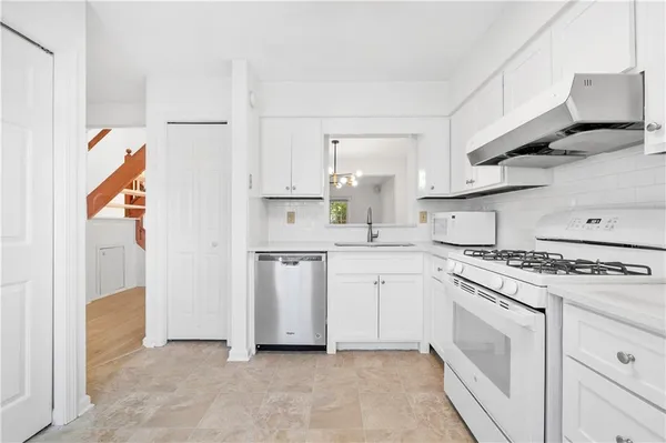 a kitchen with white cabinets and white appliances