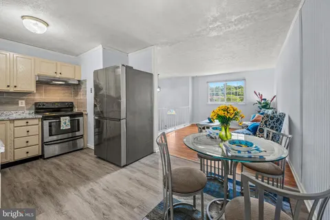 a kitchen with stainless steel appliances kitchen island granite countertop a dining table chairs and refrigerator