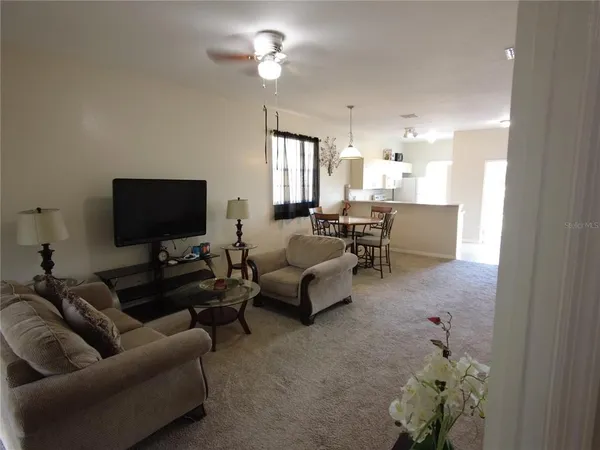 a living room with furniture a chandelier and a flat screen tv