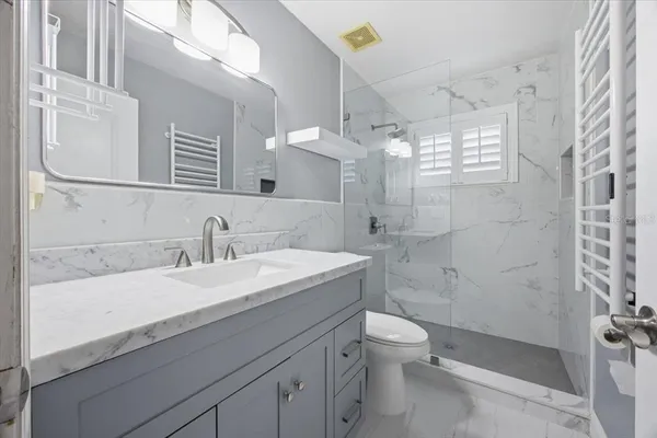 a bathroom with a sink a toilet a mirror and shower