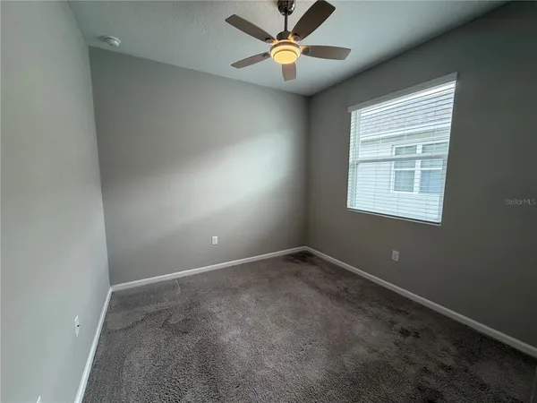 an empty room with a window and a fan