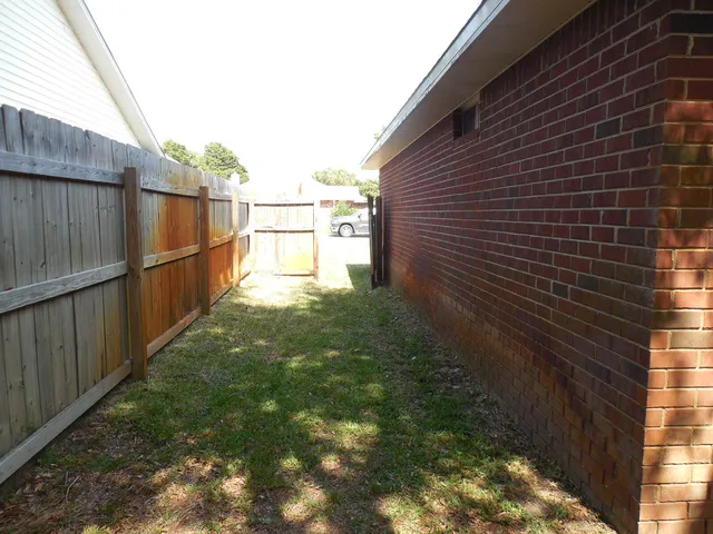 a view of an empty room with window and chandelier fan