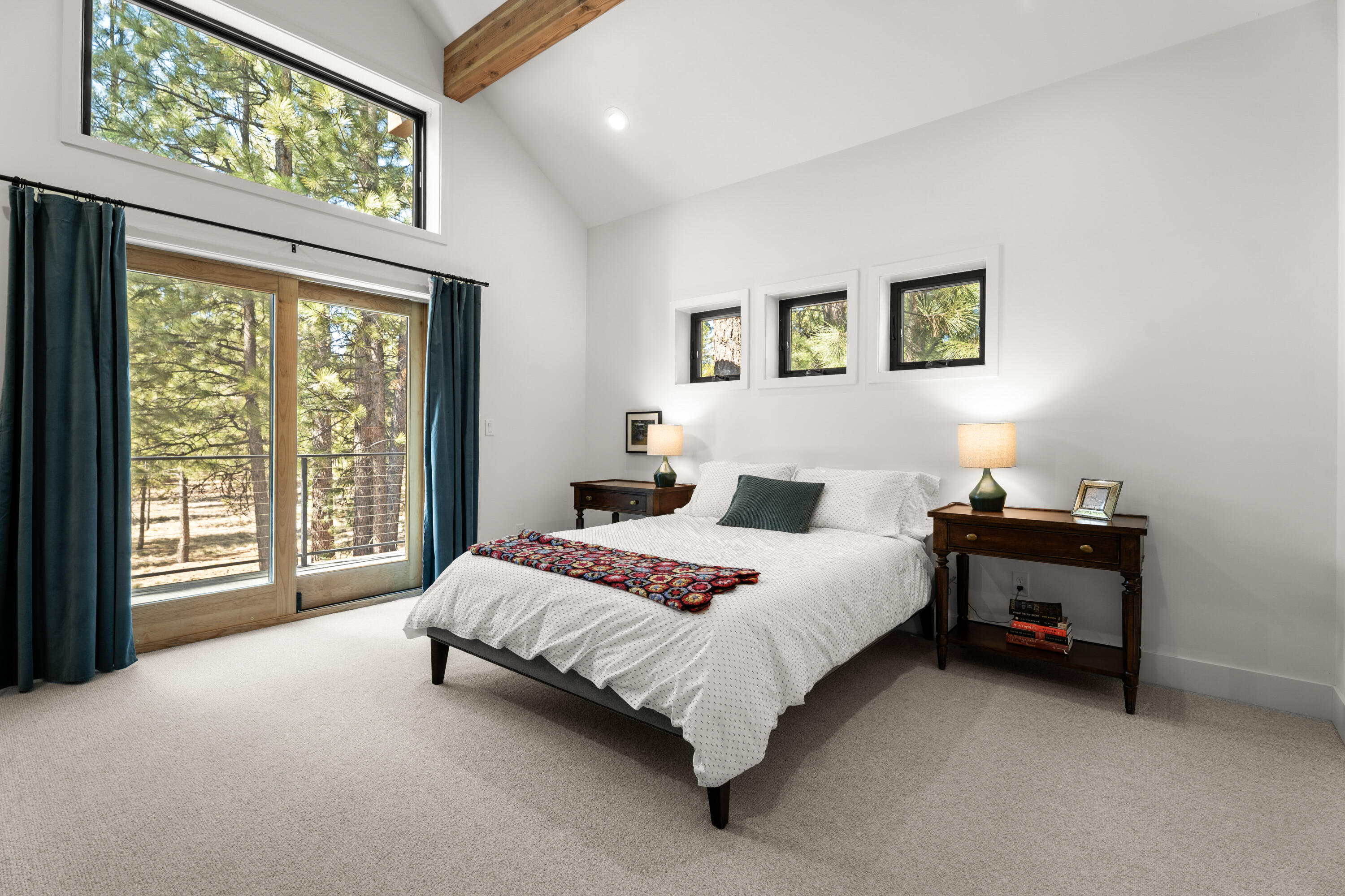 56670 Sunstone Loop, Unit LOT 141 Bend, OR 97707 - Photo 17 of 62 Light-filled second-level bedroom with vaulted ceiling, exposed glulam beam detail, soft Hibernia Woolen Mills carpet, and sliding door access to a private balcony overlooking the pines.