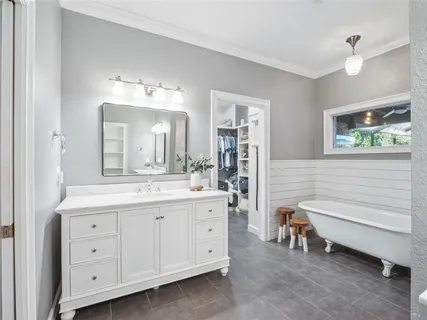 a bathroom with a double vanity sink a mirror a bathtub and a window