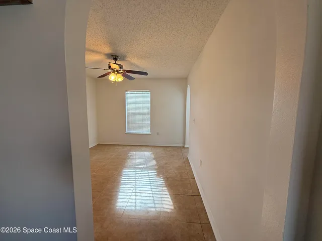 a view of an empty room and chandelier fan