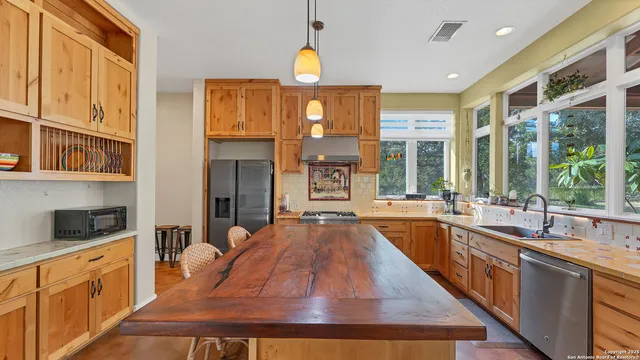a large kitchen with kitchen island granite countertop a large window and stainless steel appliances