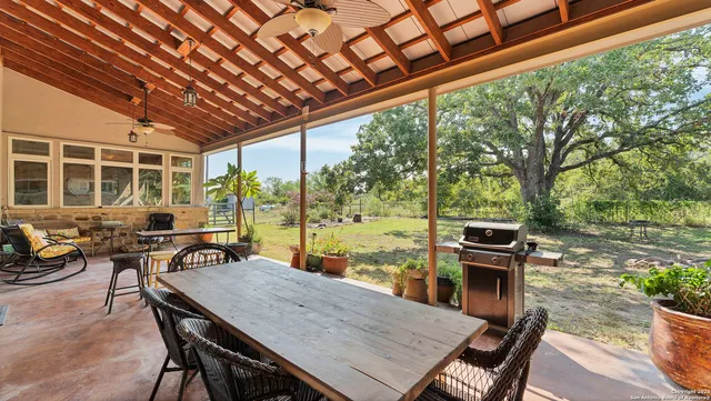 a view of a patio with couches table and chairs potted plants and floor to ceiling window