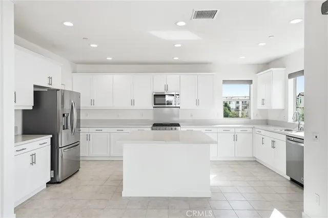 a view of an empty room with kitchen and window