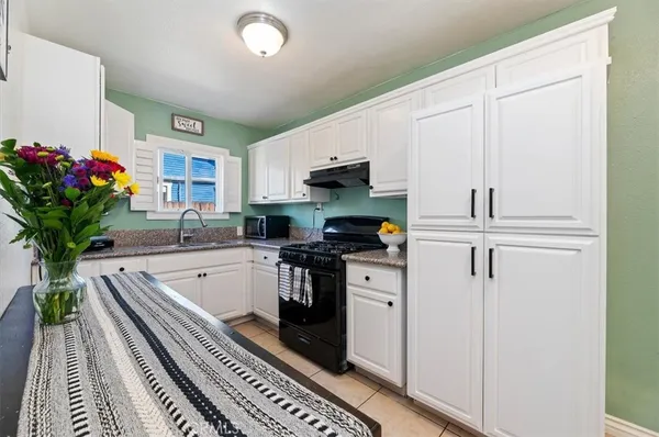 a kitchen with granite countertop a sink stove and cabinets