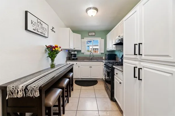 a kitchen with stainless steel appliances a stove a chimney a sink and cabinets