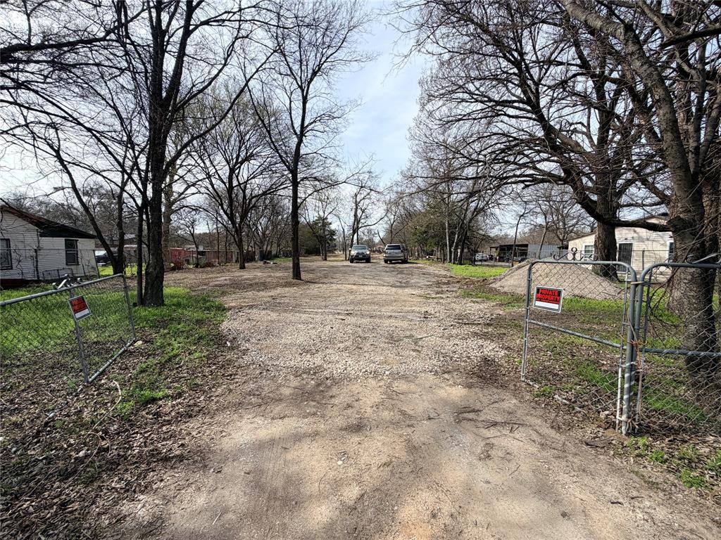 4151 Interurban Road Lancaster, TX 75134 - Photo 2 of 8 View of dirt / gravel driveway featuring a gated entry, a gate, and a residential view