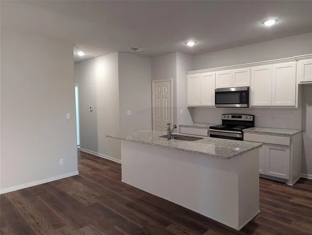 a kitchen with granite countertop a sink and a stove top oven
