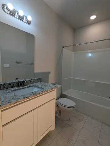 a bathroom with a granite countertop sink a toilet and a shower