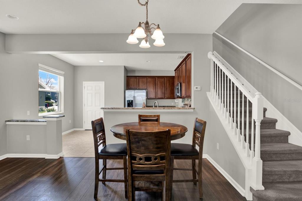 10228 Red Currant Court Riverview, FL 33578 - Photo 12 of 37 a dining room with wooden floor a chandelier a wooden table and chairs