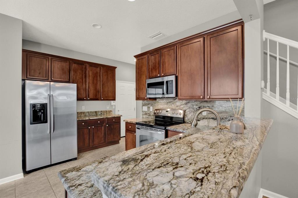 10228 Red Currant Court Riverview, FL 33578 - Photo 14 of 37 a kitchen with stainless steel appliances granite countertop a refrigerator stove top oven a sink and dishwasher