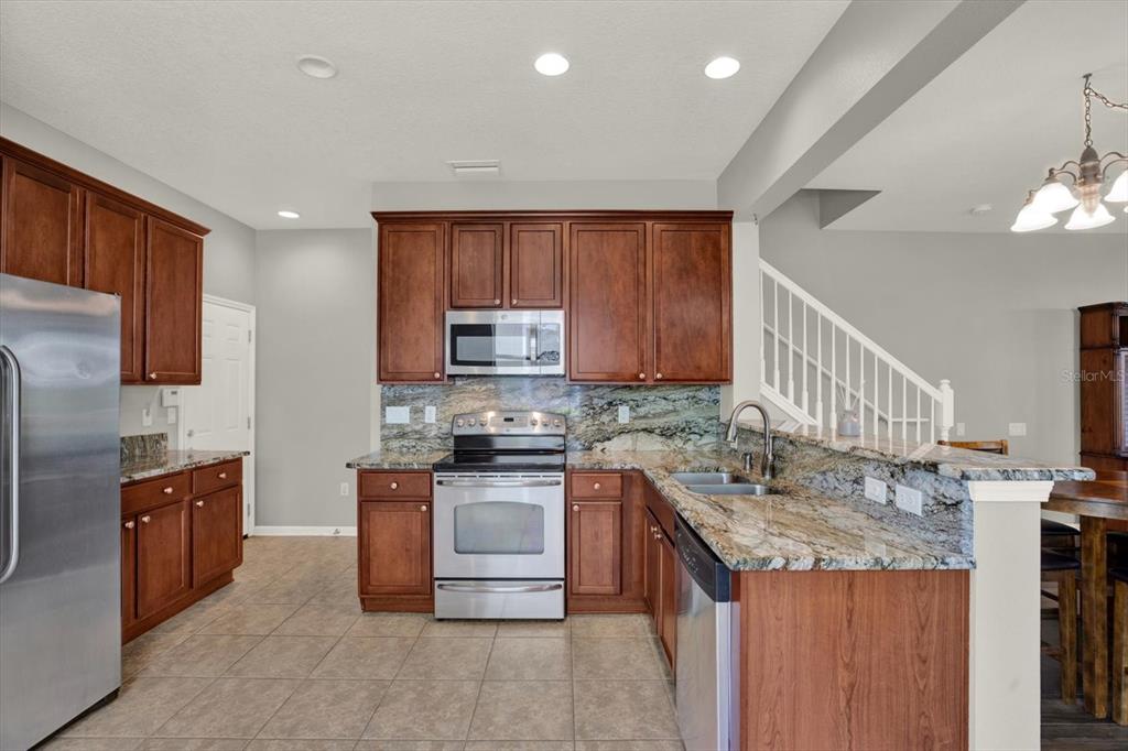 10228 Red Currant Court Riverview, FL 33578 - Photo 15 of 37 a kitchen with stainless steel appliances granite countertop a sink stove and refrigerator