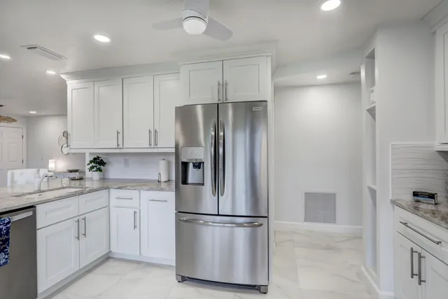 a kitchen with stainless steel appliances kitchen island granite countertop a dining table chairs refrigerator and sink