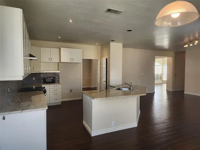 a kitchen with granite countertop white cabinets and stainless steel appliances