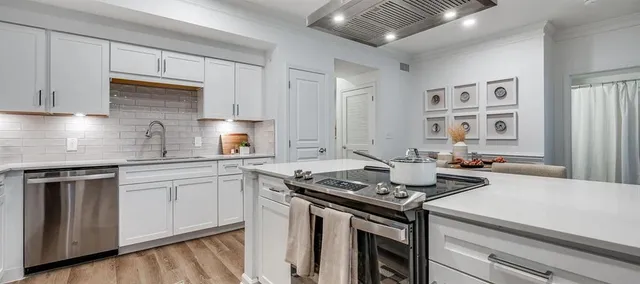 a open kitchen with stainless steel appliances granite countertop a stove top oven a dining table and chairs with wooden floor