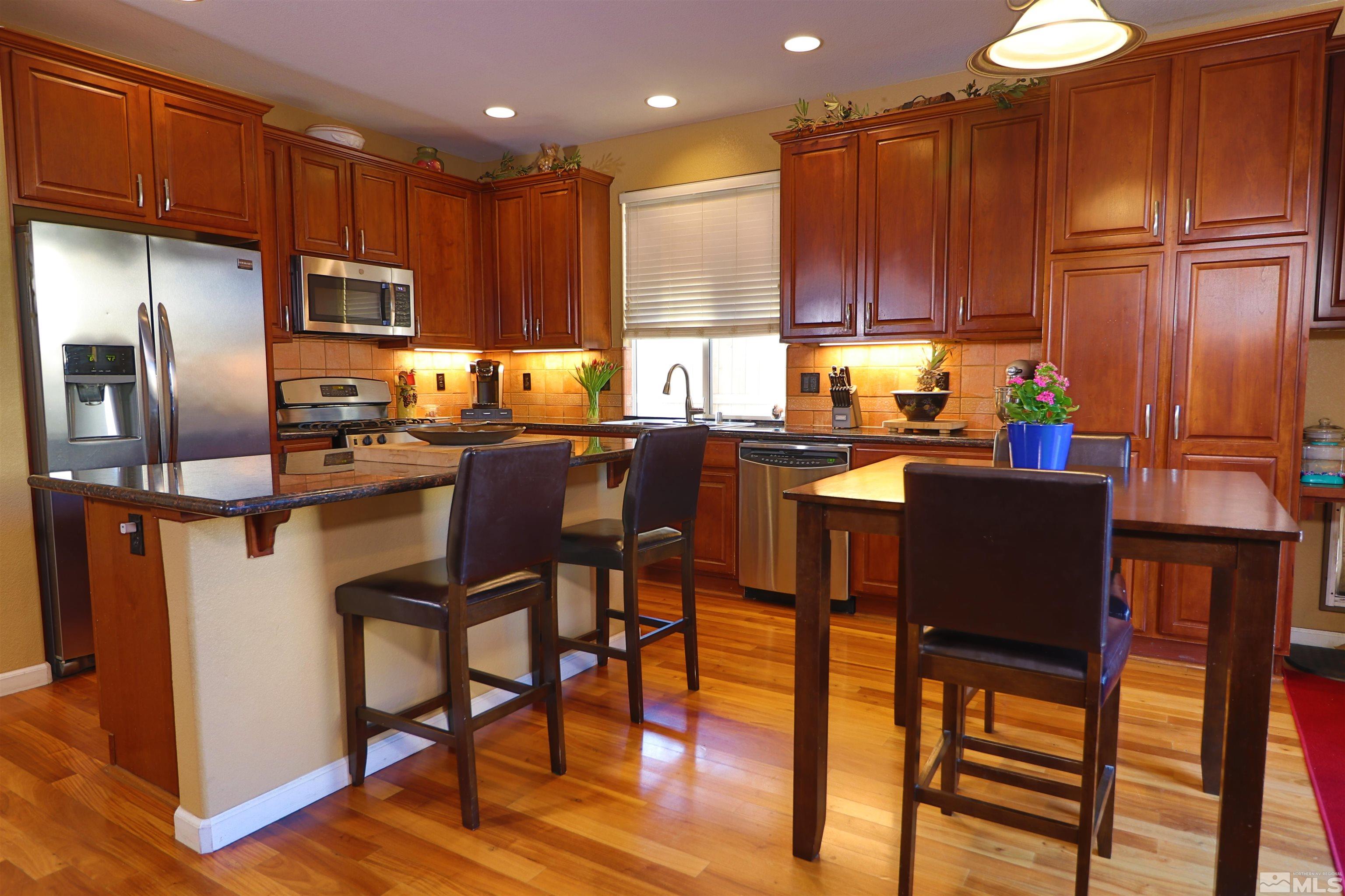 2491 Spring Flower Drive Reno, NV 89521 - Photo 4 of 19 a kitchen with stainless steel appliances granite countertop a refrigerator a stove a sink a dining table and chairs with wooden floor