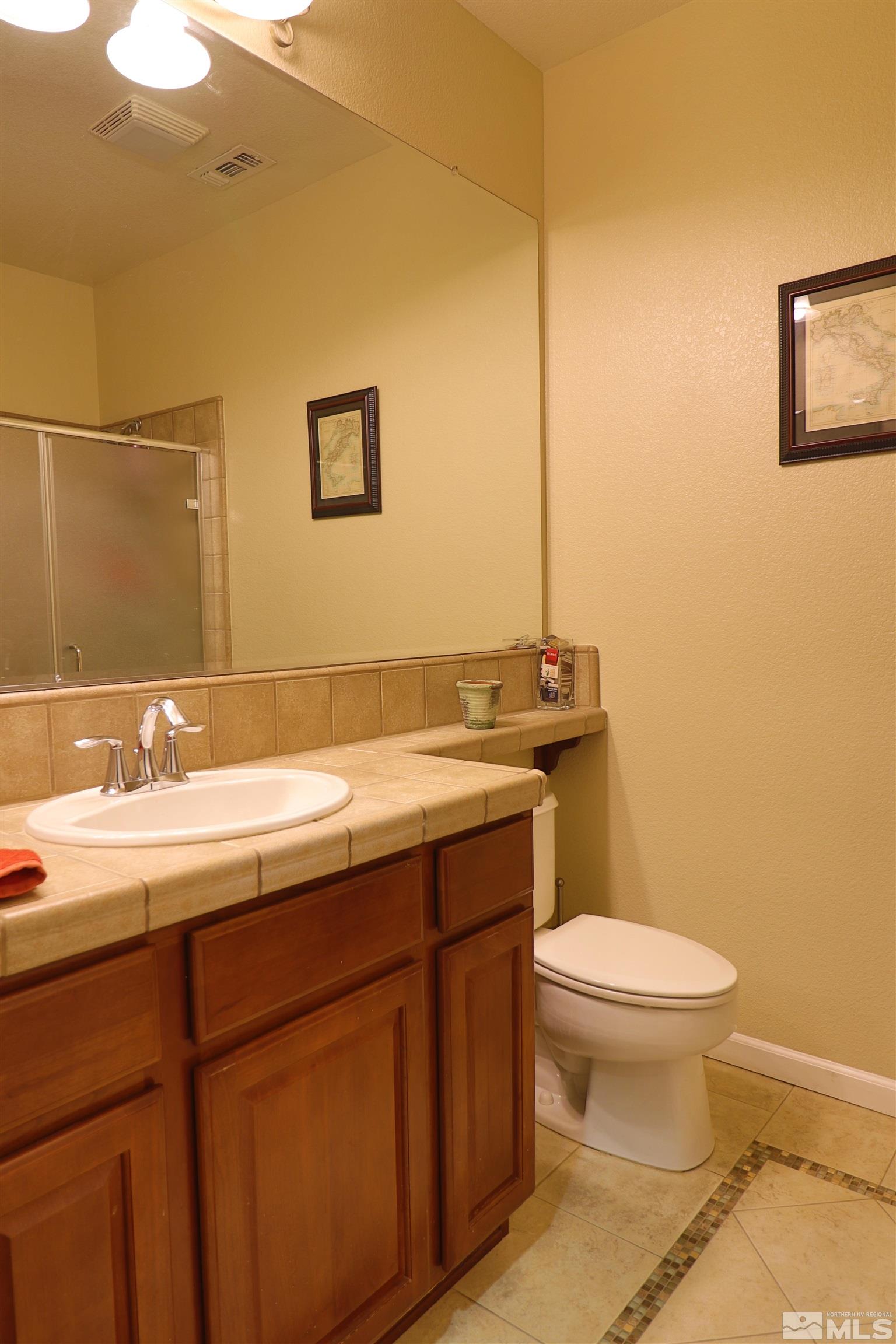 2491 Spring Flower Drive Reno, NV 89521 - Photo 7 of 19 a bathroom with a granite countertop toilet sink and mirror