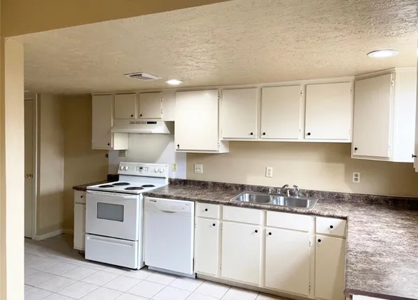 a kitchen with granite countertop white cabinets and white appliances