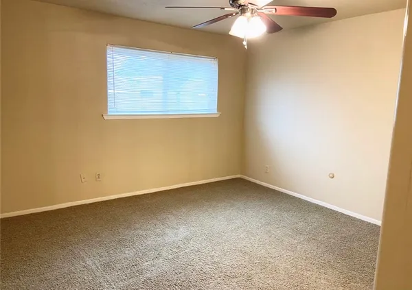 an empty room with a chandelier fan and windows
