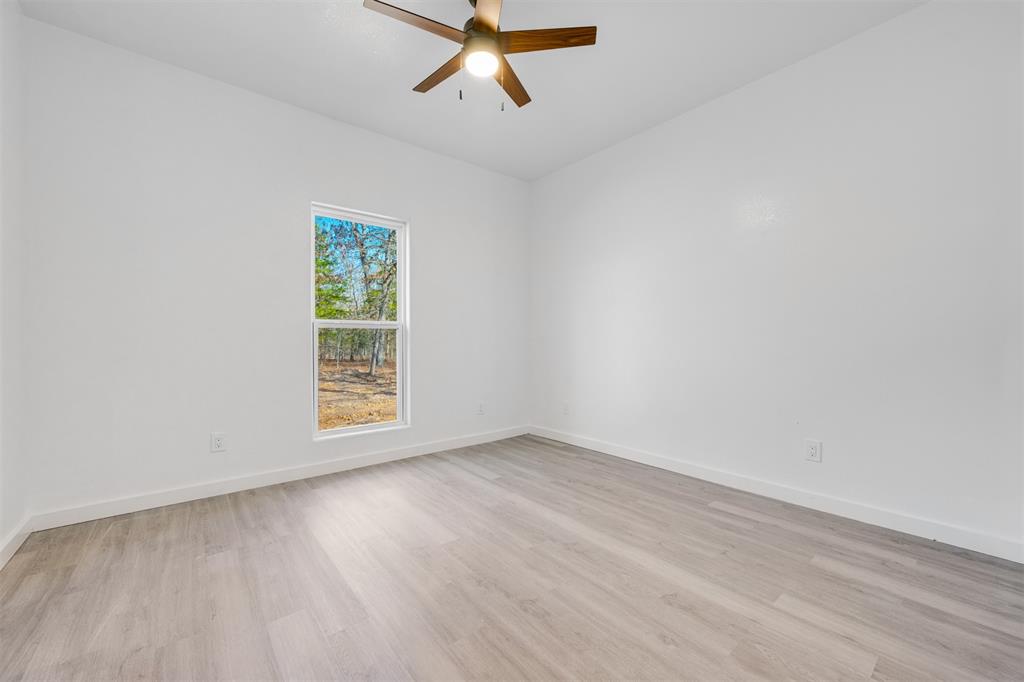 260 Private Road Sumner, TX 75486 - Photo 16 of 23 an empty room with wooden floor ceiling fan and windows