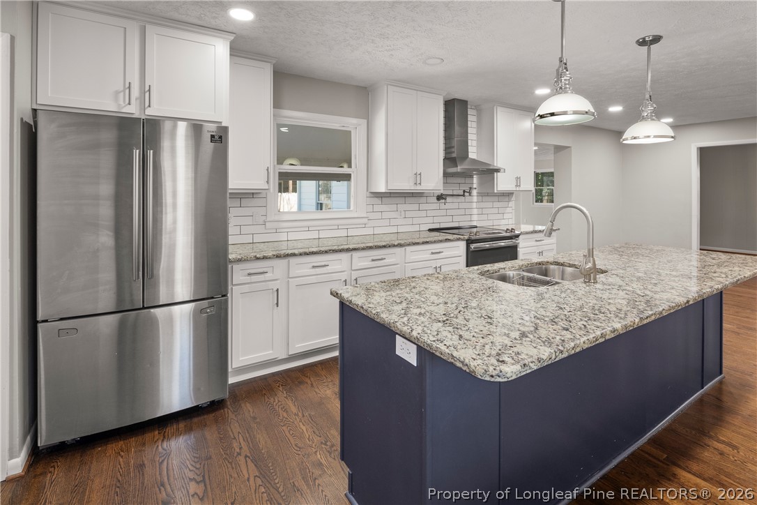 4196 Cliffdale Road Fayetteville, NC 28303 - Photo 11 of 38 a kitchen with kitchen island granite countertop a sink stove a refrigerator and a wooden floor