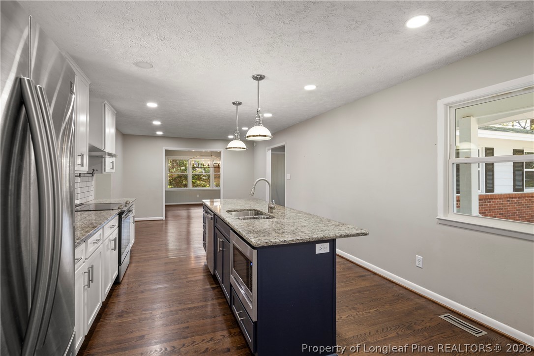 4196 Cliffdale Road Fayetteville, NC 28303 - Photo 12 of 38 a kitchen with stainless steel appliances granite countertop a refrigerator a sink dishwasher a stove and a dining table with wooden floor