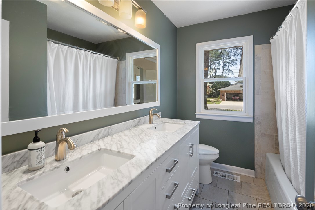 4196 Cliffdale Road Fayetteville, NC 28303 - Photo 26 of 38 a bathroom with a granite countertop sink mirror vanity and toilet