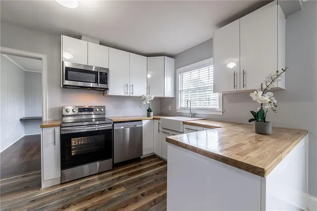 a kitchen with stainless steel appliances granite countertop a sink dishwasher a stove and a microwave oven with white cabinets