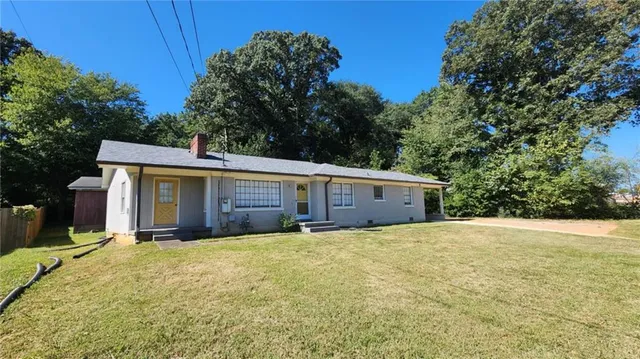 a front view of house with yard and trees in the background