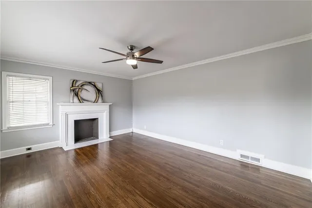 an empty room with wooden floor a ceiling fan and windows