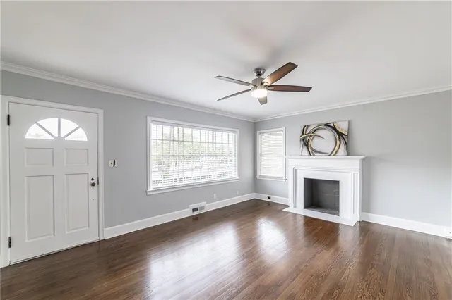an empty room with wooden floor a ceiling fan and windows