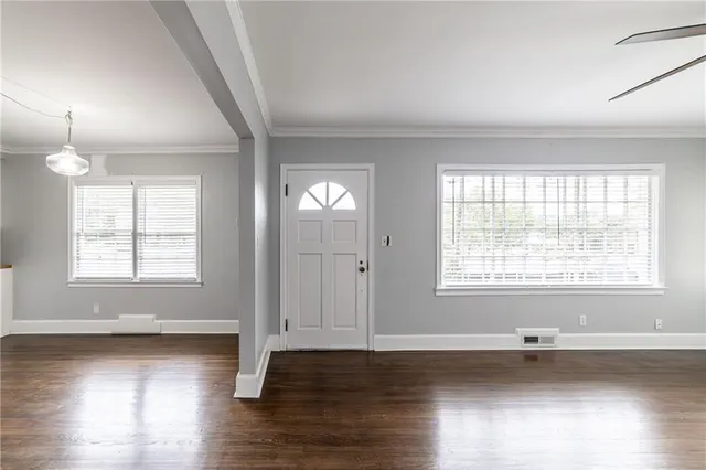 an empty room with wooden floor and windows