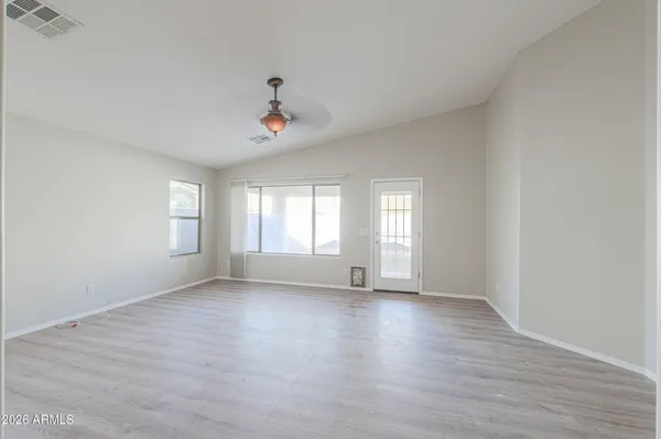 a view of an empty room with a window and wooden floor