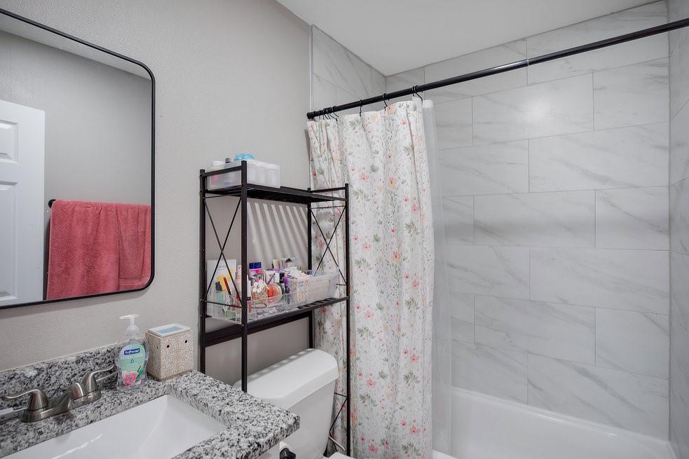 4029 Knox Street Fort Worth, TX 76119 - Photo 19 of 28 a bathroom with a shower curtain and a bathtub