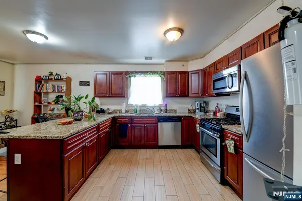 a kitchen with stainless steel appliances granite countertop wooden cabinets a stove top oven a sink and dishwasher