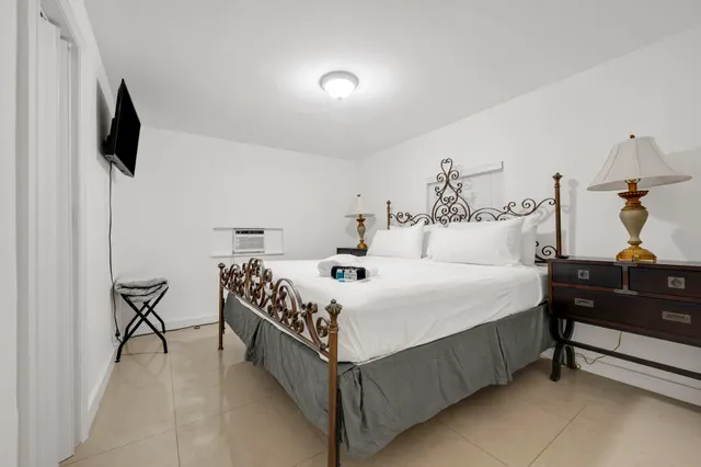 a bedroom with a bed and a flat tv screen on the dresser