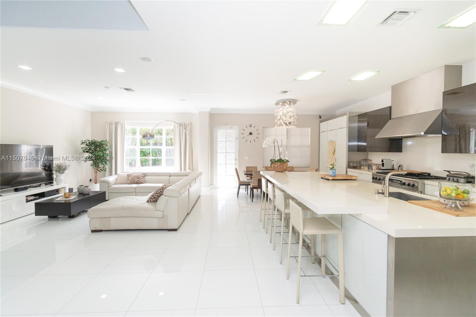 a large white kitchen with lots of counter space a sink appliances and a large window