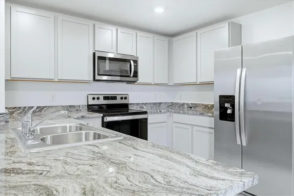 a kitchen with stainless steel appliances granite countertop a refrigerator sink and stove